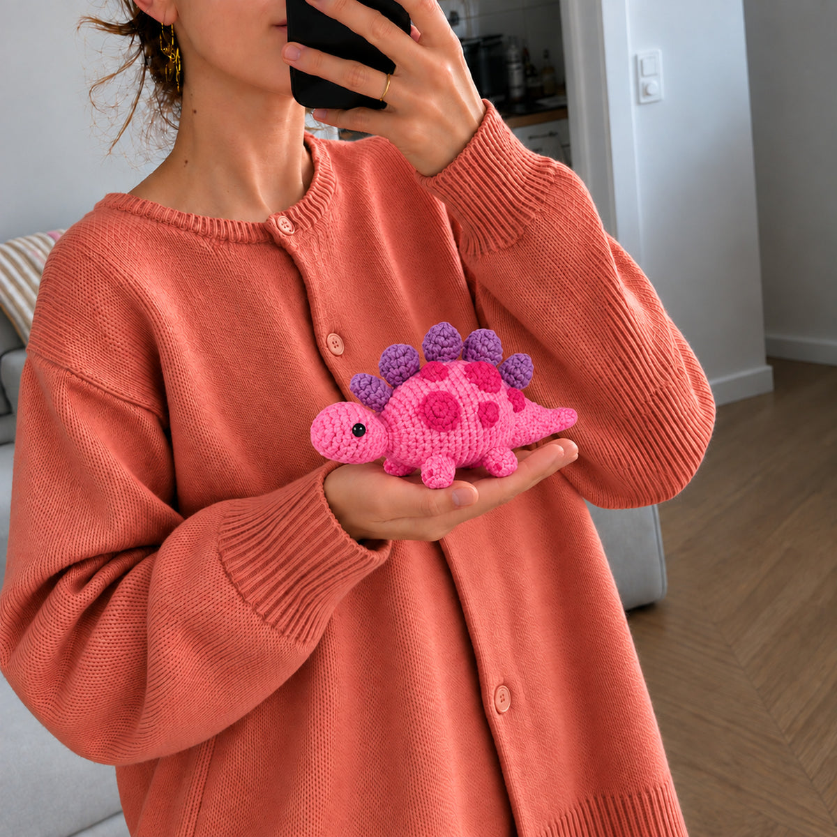 Berry Little Dino: a berry pink dinosaur with purple plates along its back, shown in hand