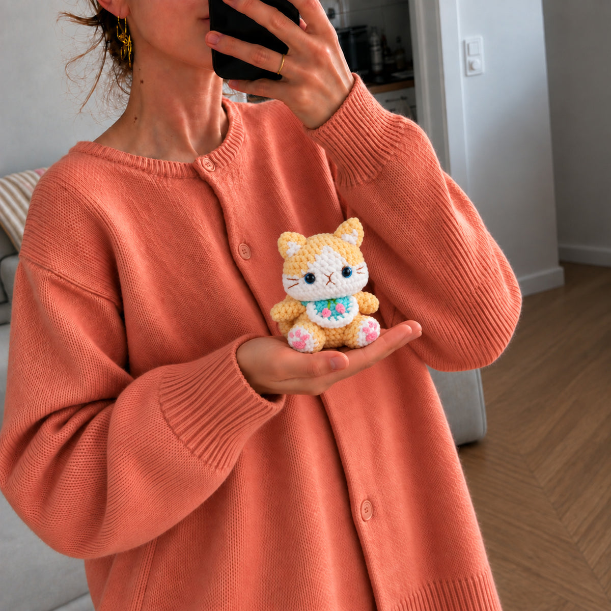 Buttercup Bloom Kitty: a golden yellow kitten with bright blue eyes and a little floral bib, shown in hand