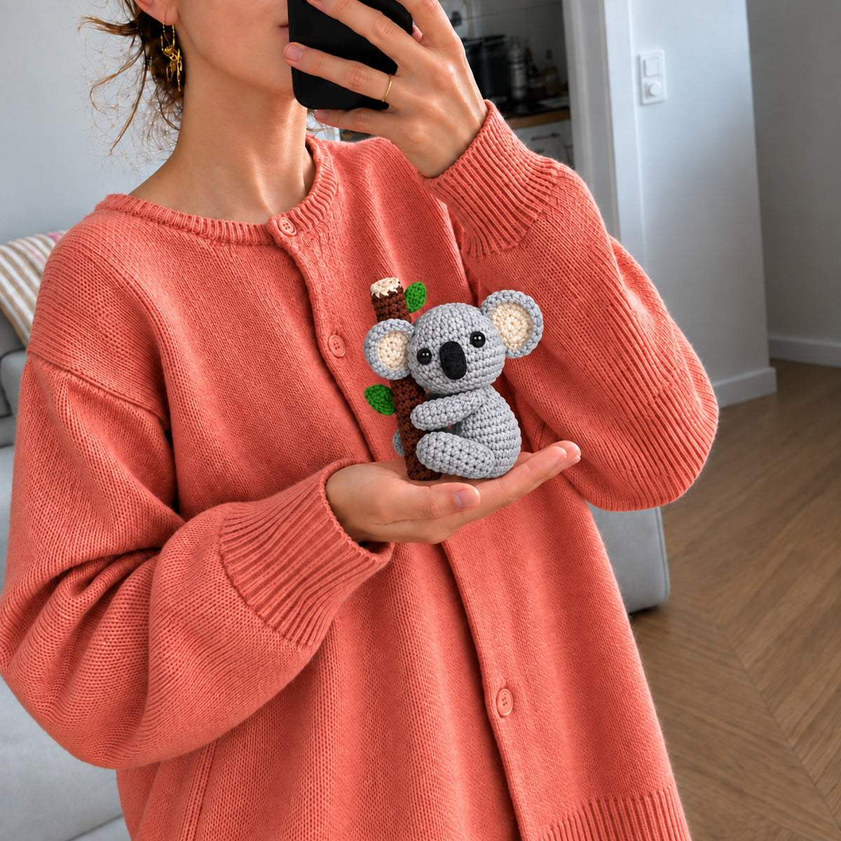 Eucalyptus Koala: a grey koala holding onto a little leafy branch, shown in hand