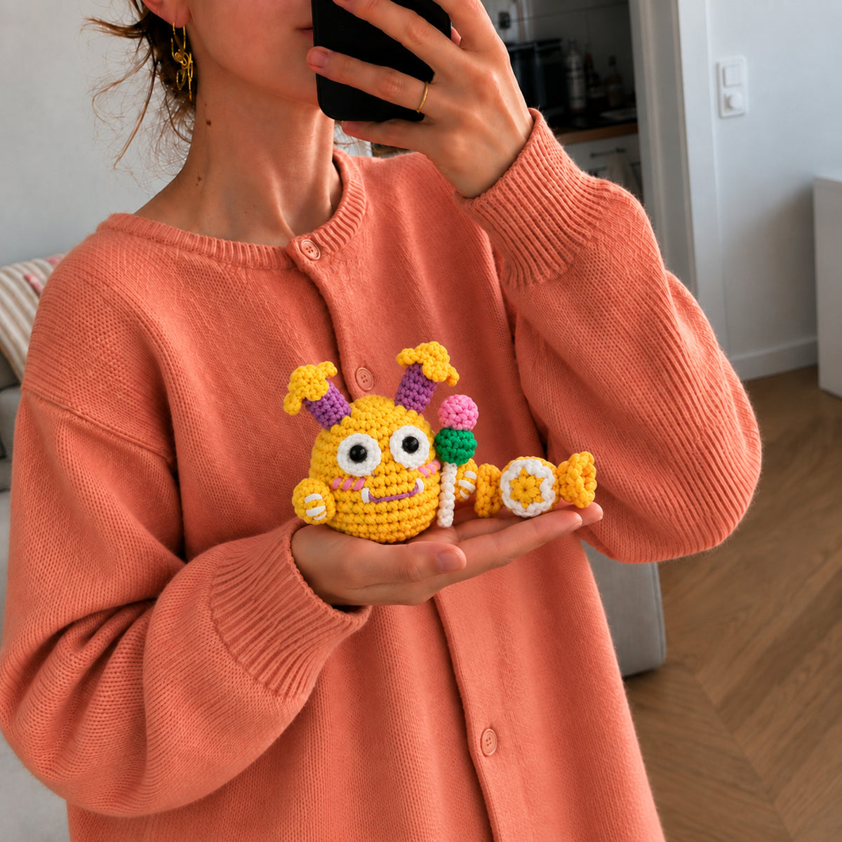 Sunny Pop Monster: a sunny yellow monster with colourful flower details, shown in hand
