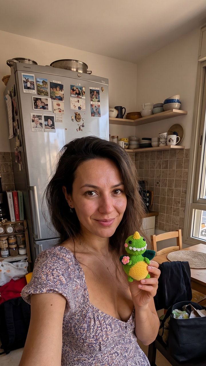 Crafter in a kitchen holding a green crocheted character