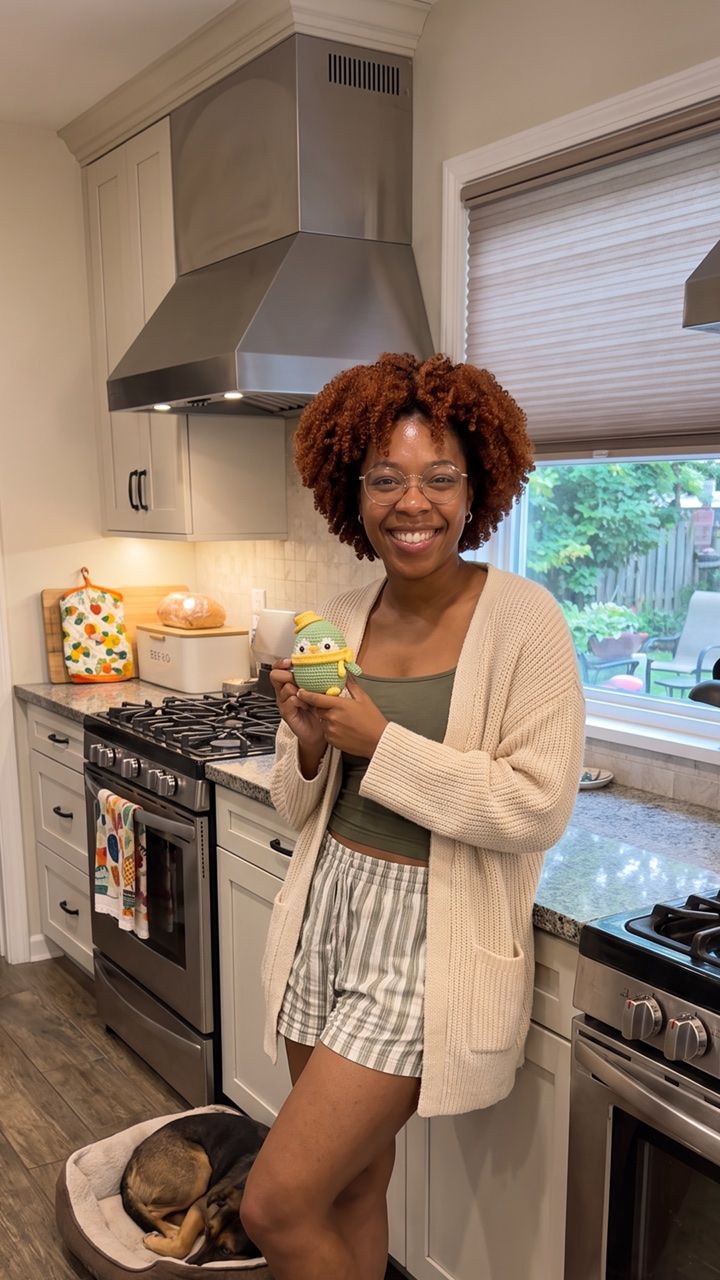 Crafter in a kitchen holding a green crochet project