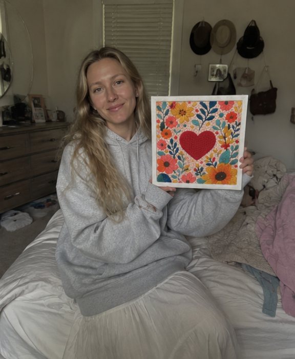 Crafter seated at home holding a heart artwork