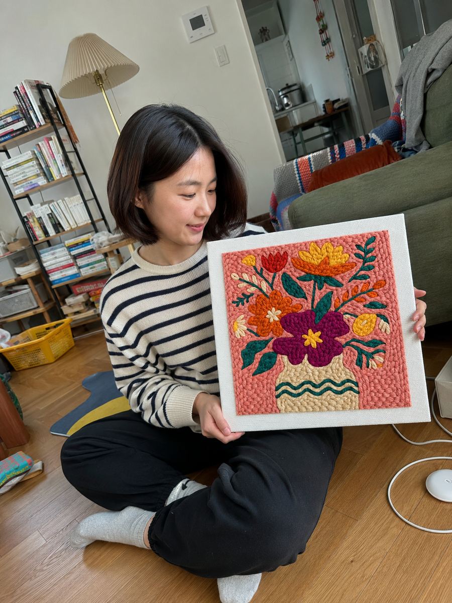 Crafter seated with a colorful floral artwork
