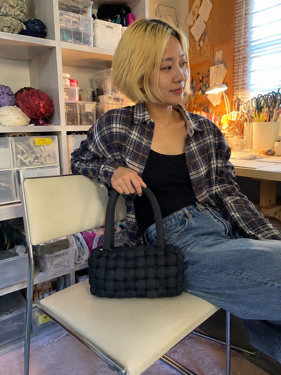 Crafter seated in a studio with a handmade black crochet bag