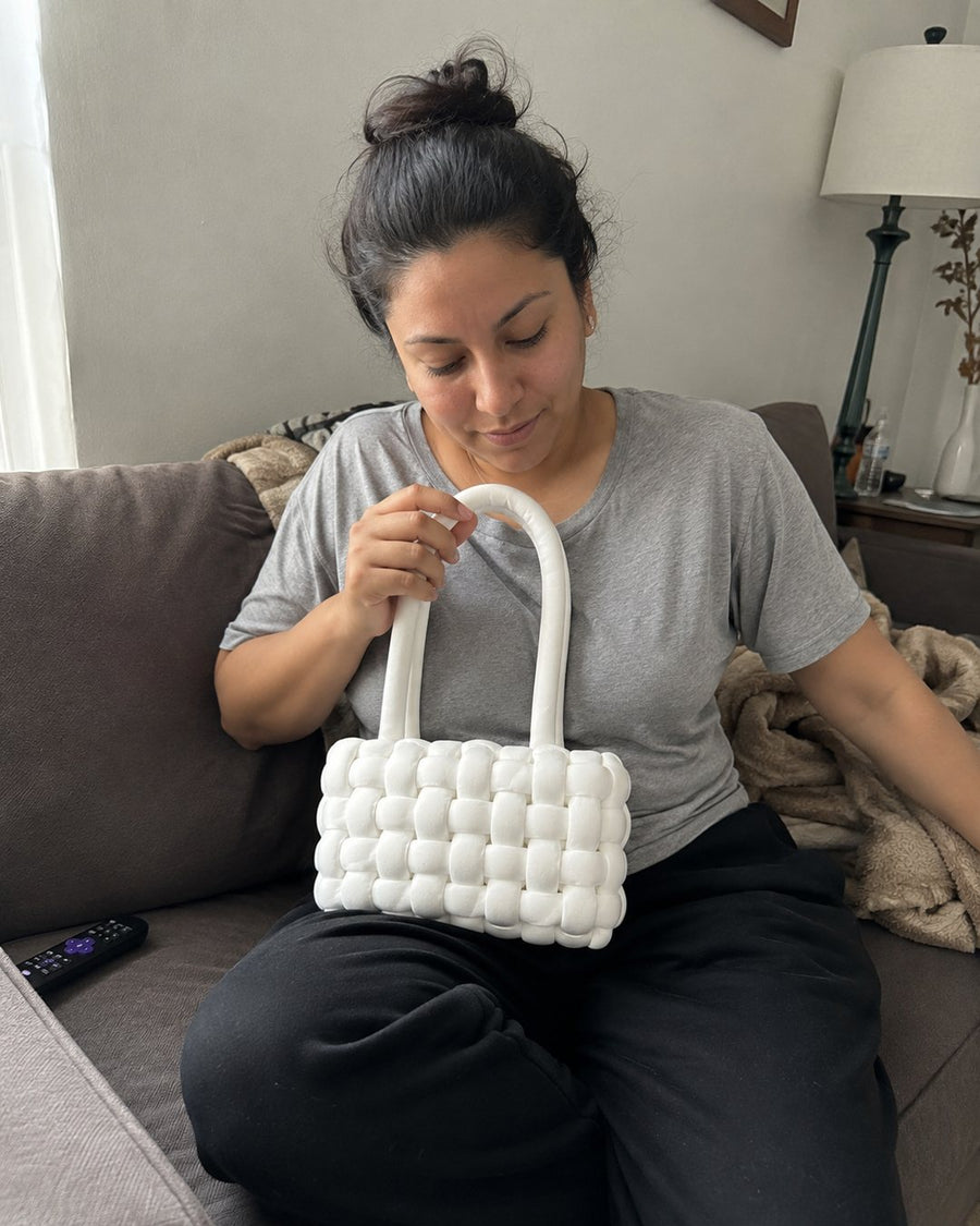Crafter seated while finishing a white crochet bag