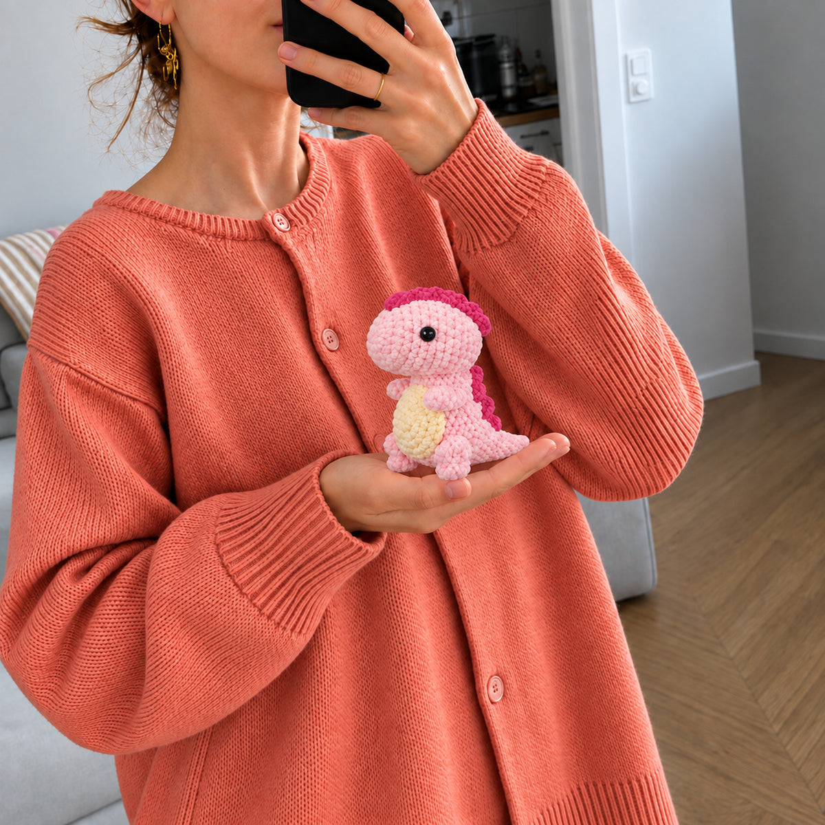 Blossom Little Dino: a pink standing dinosaur with a cream belly, shown in hand