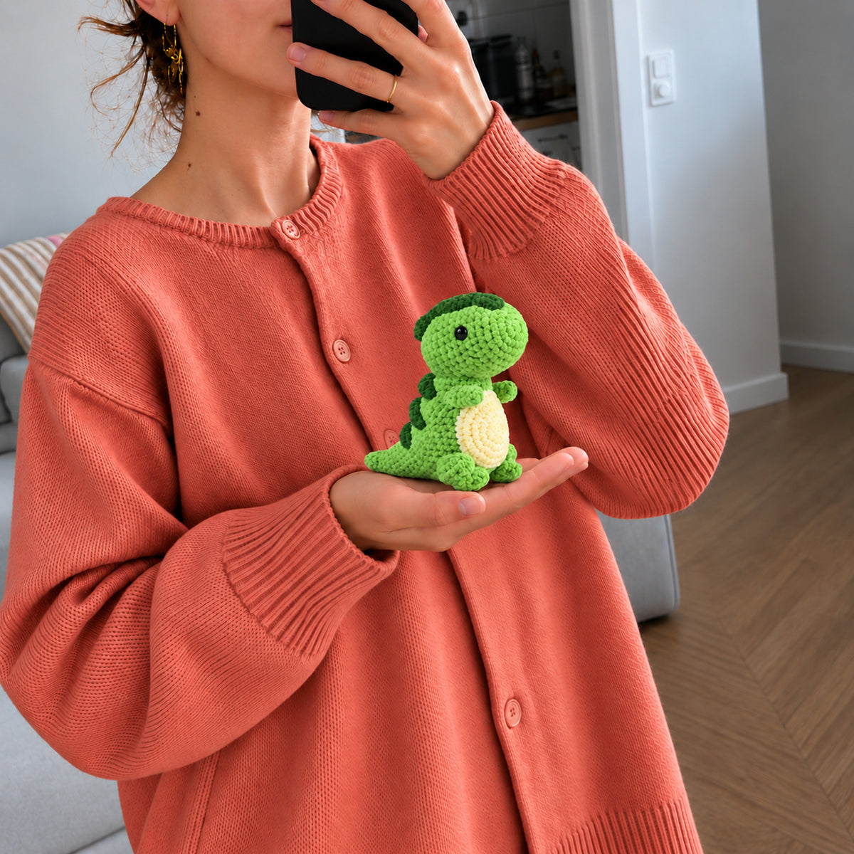 Clover Little Dino: a green standing dinosaur with a cream belly, shown in hand