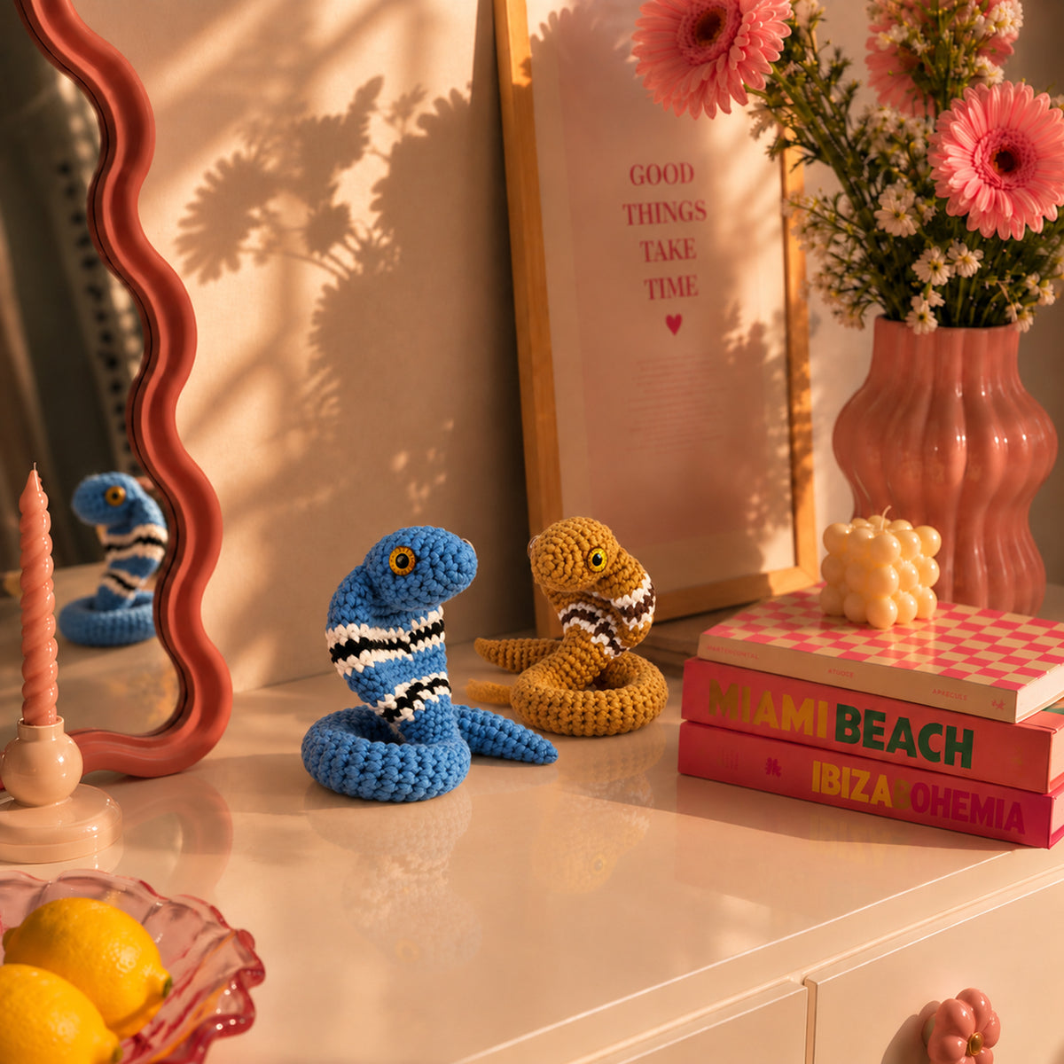 Cobra Charm Duo: blue and ochre cobras with striped markings and rounded faces, displayed in an interior setting