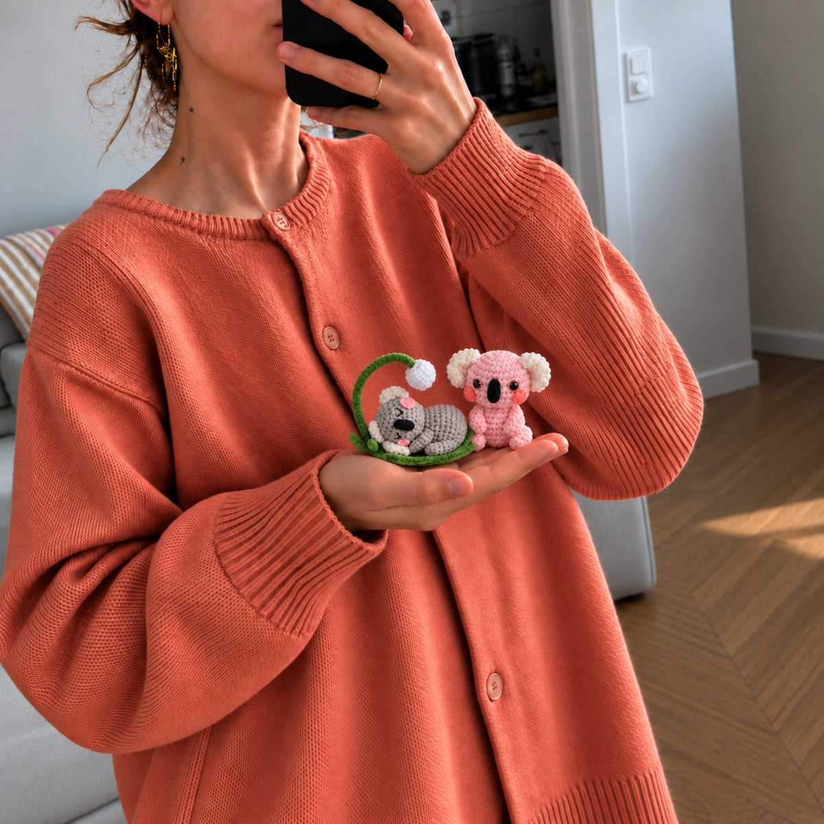 Dreamy Koala Pals: a grey koala resting in a curved branch beside a pink koala, shown in hand