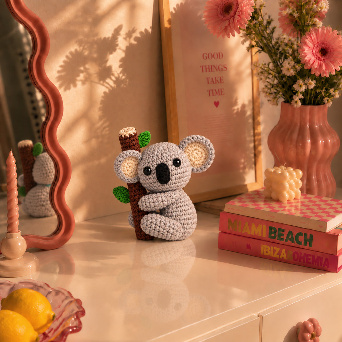 Eucalyptus Koala: a grey koala holding onto a little leafy branch, displayed in an interior setting