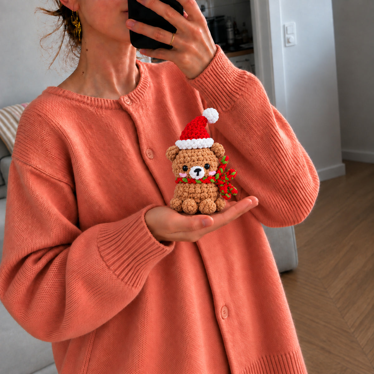 Holly Hug Bear: a brown bear in a Santa hat and festive scarf, shown in hand