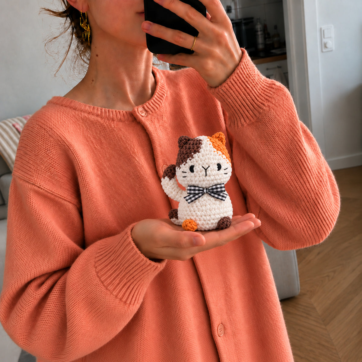 Patchwork Bow Cat: a calico cat with orange and brown patches and a checked bow, shown in hand