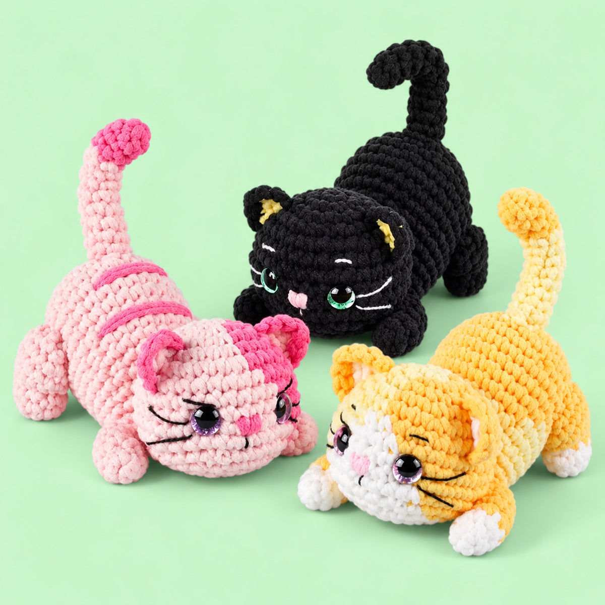 Playful Paw Trio: black, pink and yellow cats in a playful stretching pose