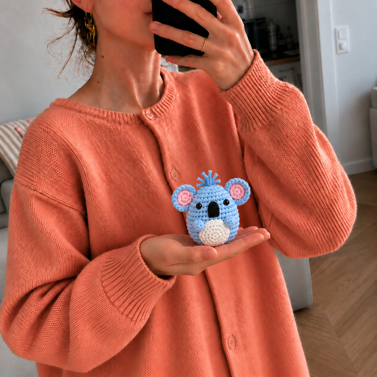 Sky Blue Koala: a sky blue koala face with pink ears and a little tuft on top, shown in hand