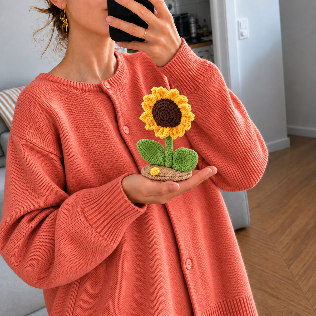 Sunflower Daydream: a golden sunflower with green leaves on a small base, shown in hand