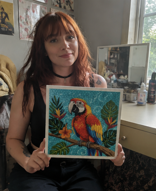 Crafter holding a parrot punch needle artwork